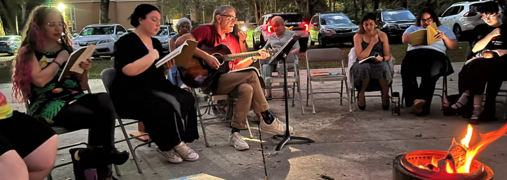 Group of musicians playing outdoors around a campfire.