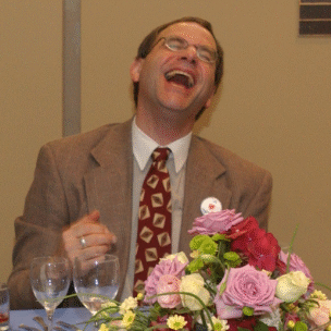 A man laughing joyfully at a table with flowers.