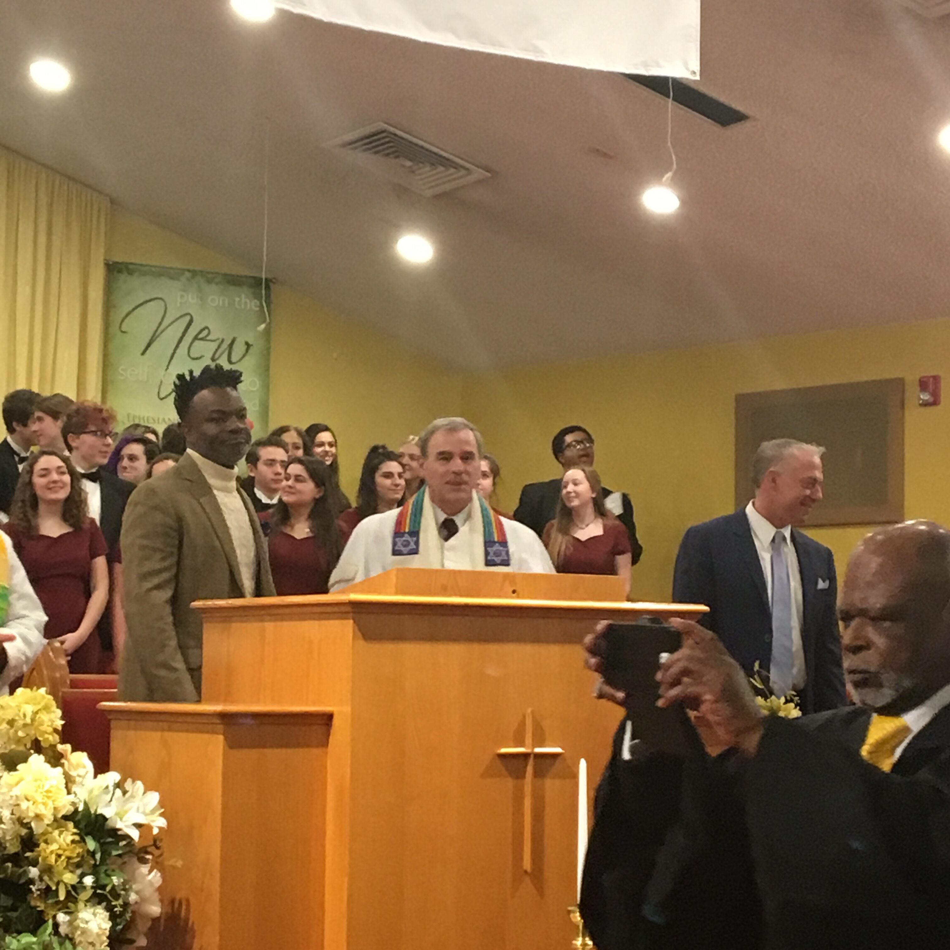 A preacher speaks passionately at a church service with choir and congregation.